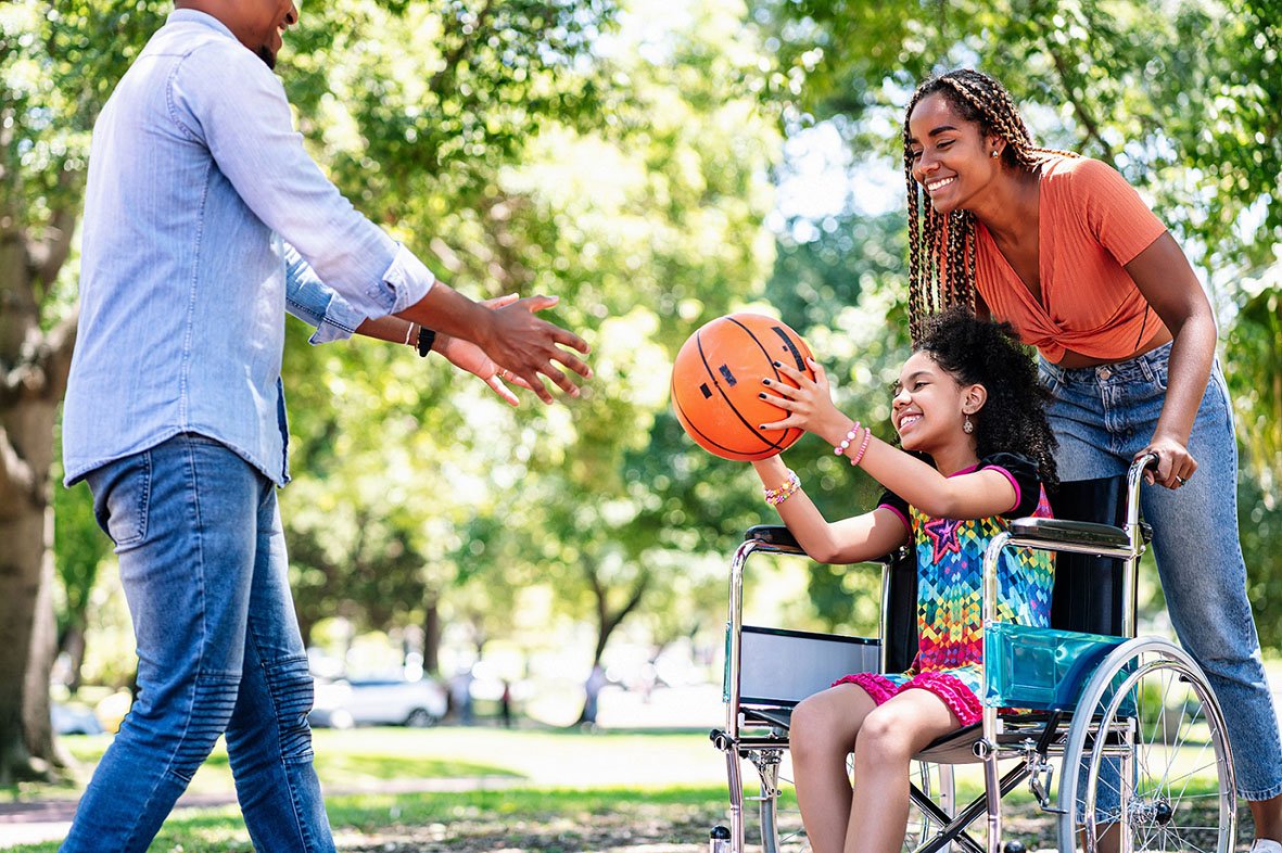 Girl in a wheelchair playing basketball with her family.